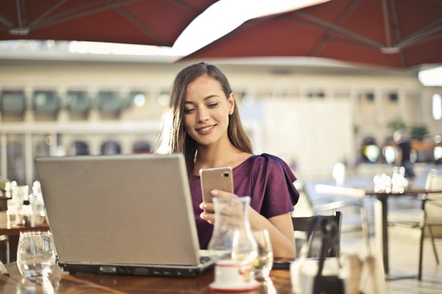 Woman holding a smartphone at a coffee shop.